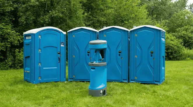 Four blue portable toilets and a matching hand washing station on grass near trees, a common sight at local outdoor events in Baton Rouge, LA