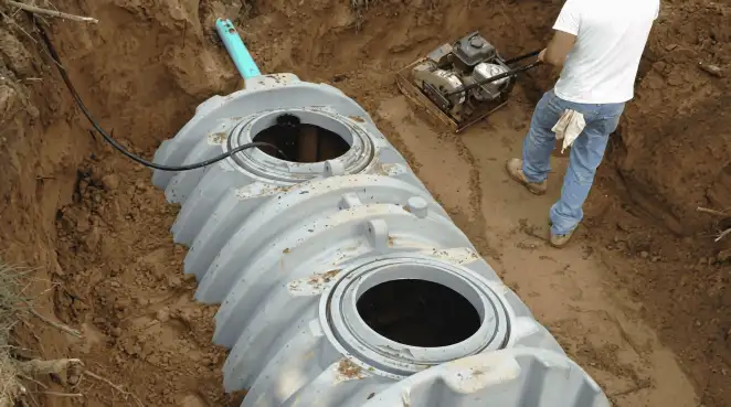 Septic tank installation showing a technician compacting soil around a new poly septic tank in an excavation pit in Baton Rouge, LA